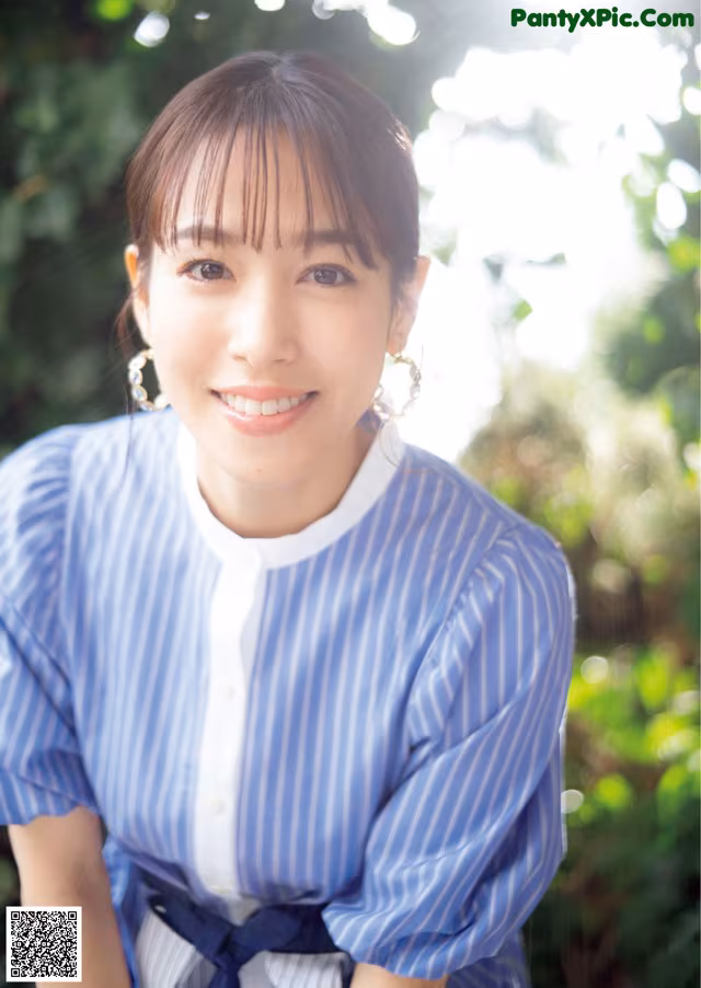 A woman in a blue and white striped shirt posing for a picture.