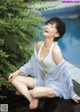 A woman sitting on a wooden deck next to a pool.