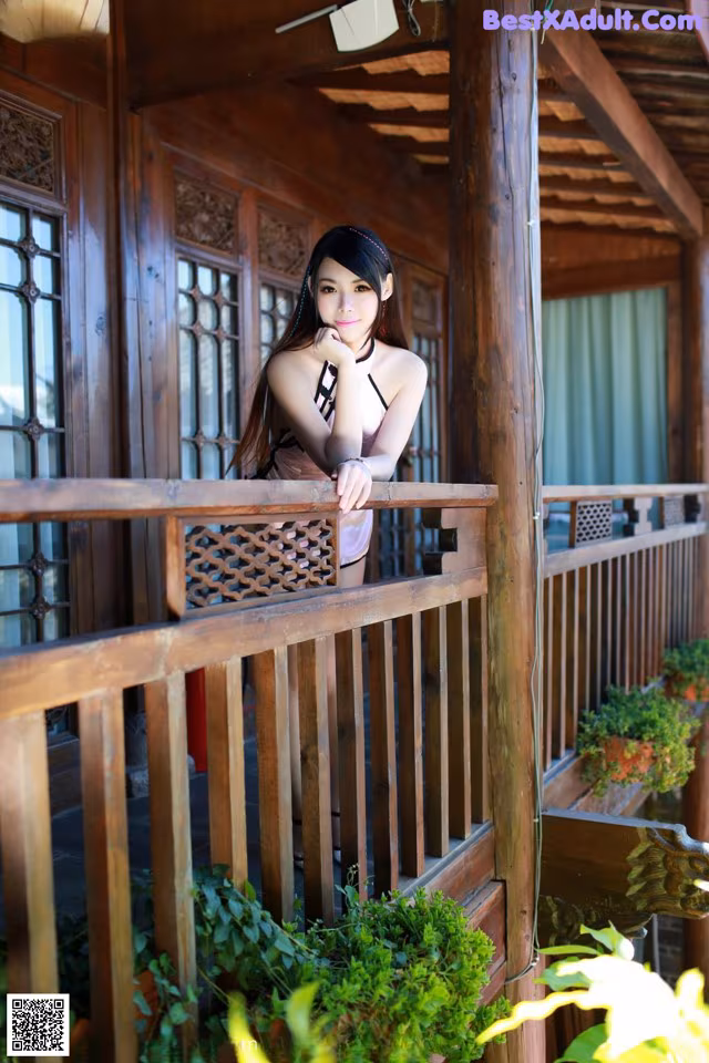 A woman standing on a wooden balcony next to a window.