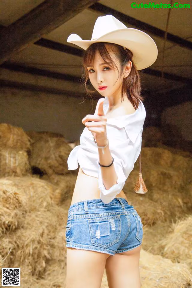 A woman in a cowboy hat pointing at the camera.