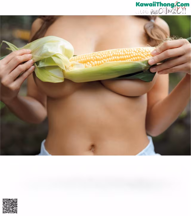 A woman holding a corn cob in front of her breasts.