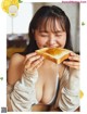 A woman eating a piece of bread with orange jam on it.