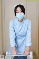 A woman in a blue uniform and a face mask.