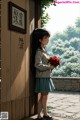 A girl holding a bunch of red roses standing in front of a door.