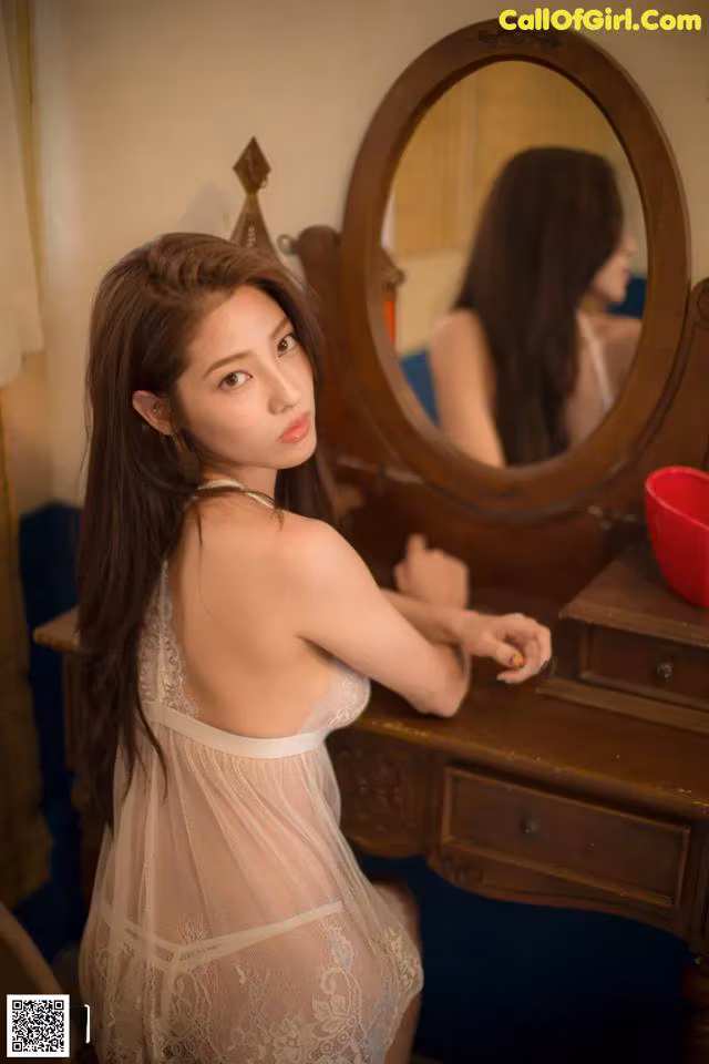 A woman in a white lingerie sitting in front of a mirror.