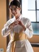 A woman in a white and gold hanbok is posing for a picture.