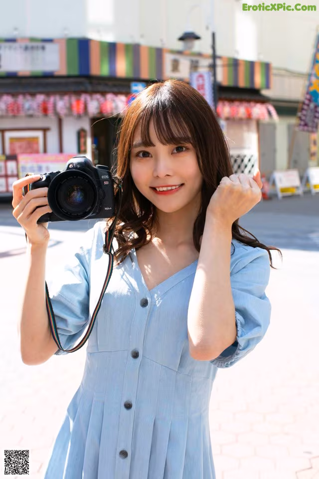 A woman in a blue dress holding a camera.