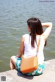 A woman sitting on the edge of a body of water.