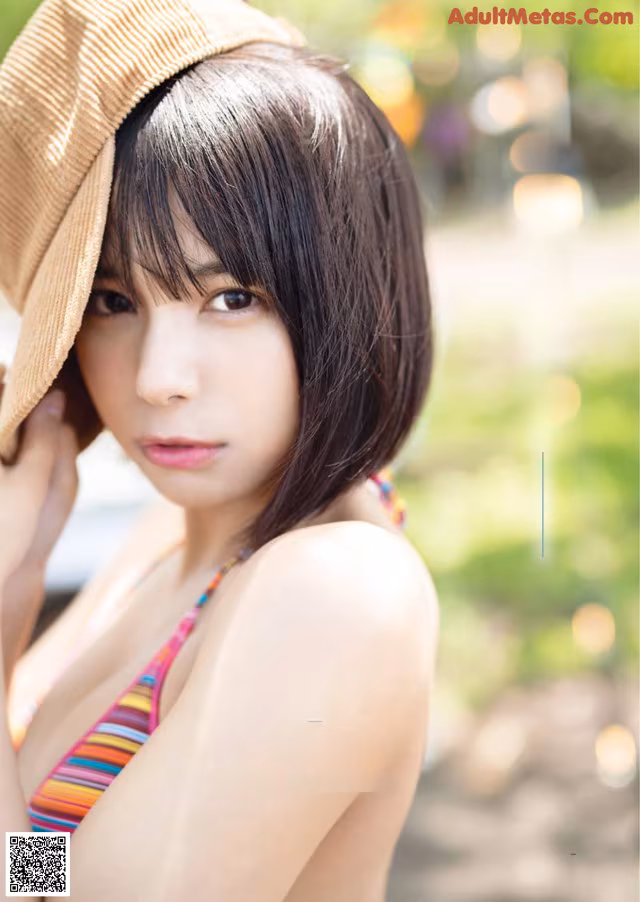 A woman in a bikini and a straw hat posing for a picture.