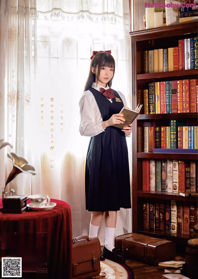A woman standing in front of a book shelf holding a book.