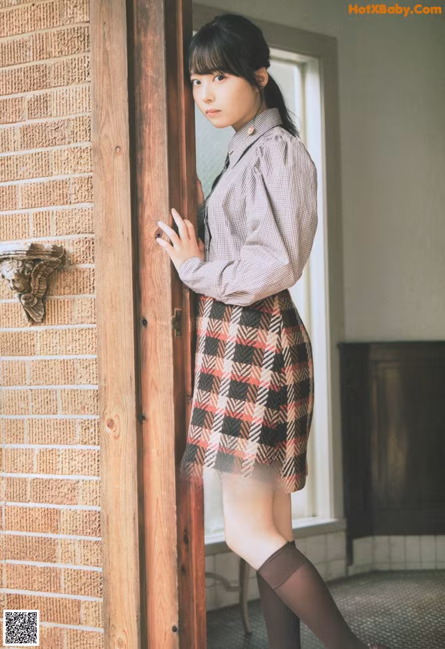 A woman standing in front of a brick wall.