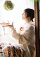 A woman sitting on the floor in front of a window.