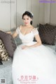 A woman in a wedding dress sitting on a couch.