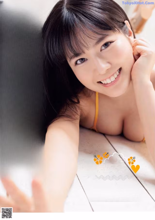 A woman in a yellow bikini laying on a wooden floor.
