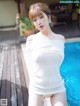 A woman in a white dress standing next to a pool.