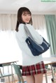 A young woman in a school uniform holding a blue bag.