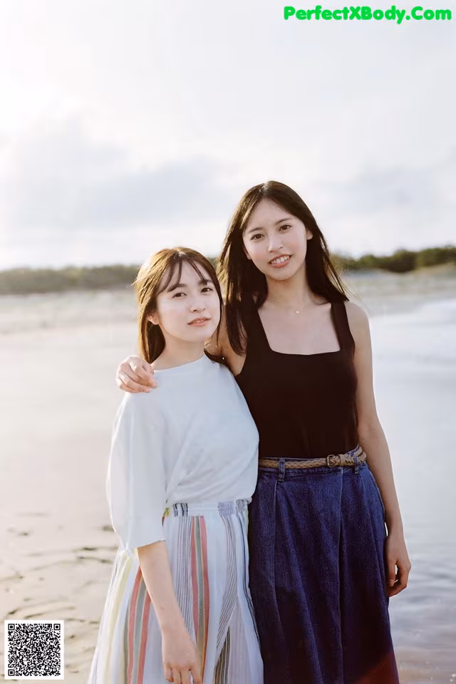 Two young women standing next to each other on a beach.