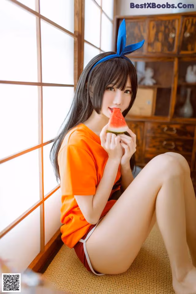 A woman sitting on the floor eating a slice of watermelon.