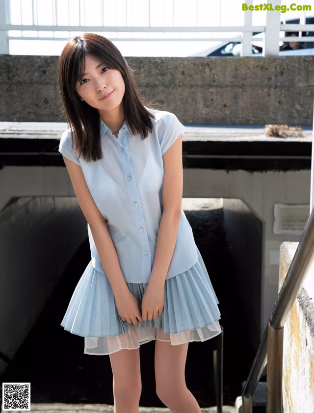 A woman in a blue shirt and skirt posing for a picture.