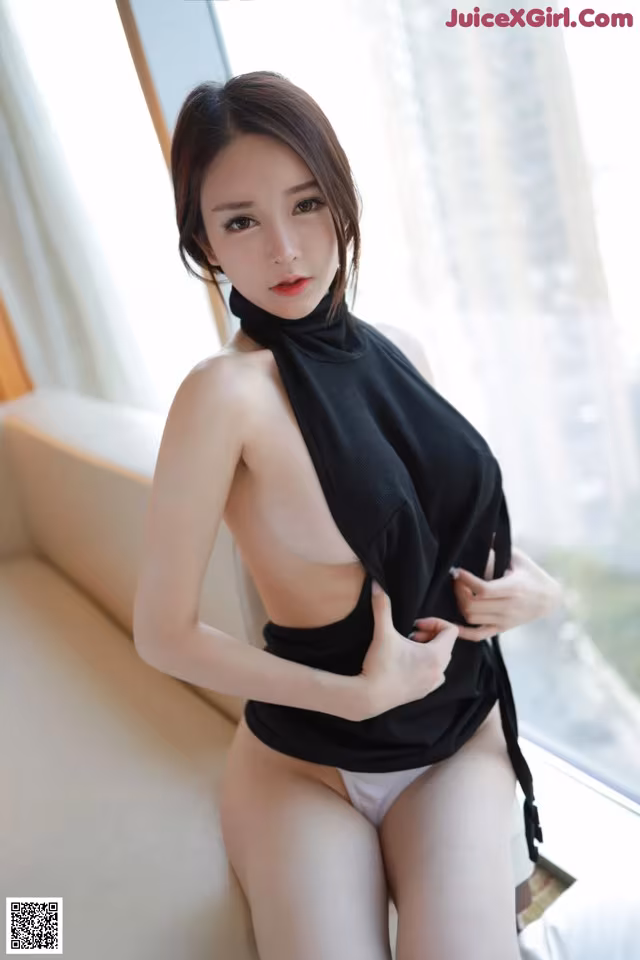 a woman in a black top and white panties sitting on a couch