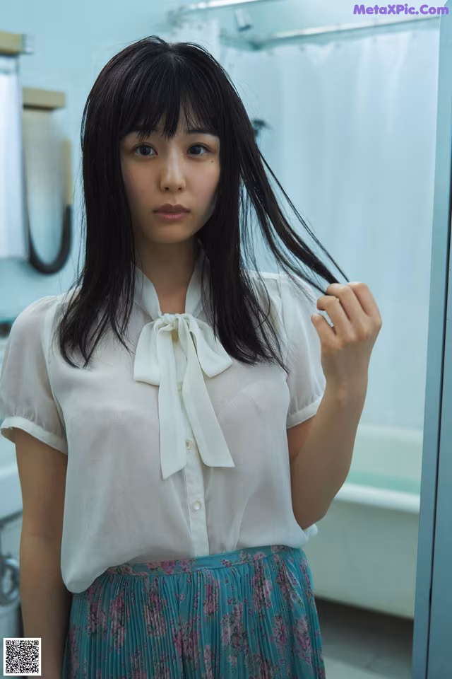 A woman standing in front of a mirror in a bathroom.
